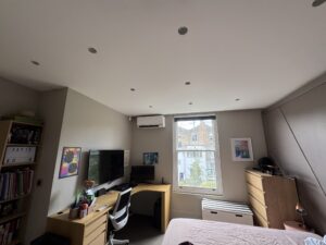 Wall-mounted air conditioning unit above the window in a Kensington bedroom with desk